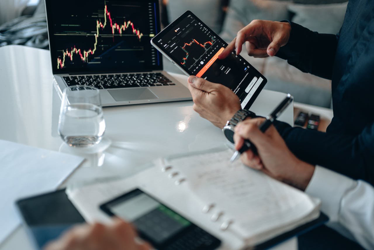 Business professionals reviewing financial charts on digital devices in a modern office setting.